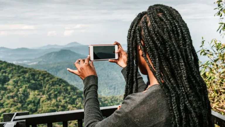 Mujer creando contenido con su móvil para redes sociales, promocionando una actividad al aire libre.