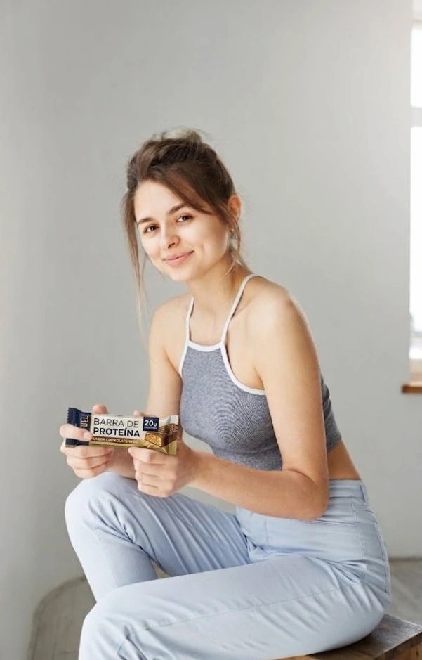Una mujer mostrando una barrita de proteínas.